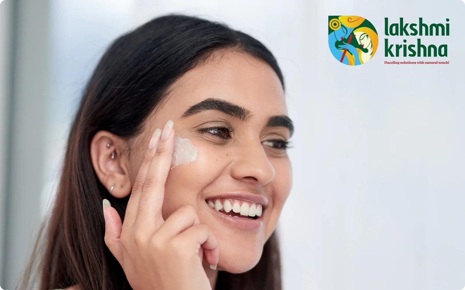 Happy woman applying face gel cream on her cheek with Lakshmi Krishna logo in background